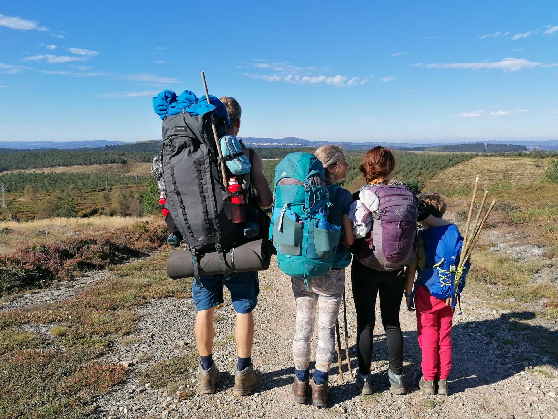 Nirmala, ihr Mann und zwei Kinder mit Rucksäcken nebeneinander auf dem Pilgerweg nach Santiago de Compostela.