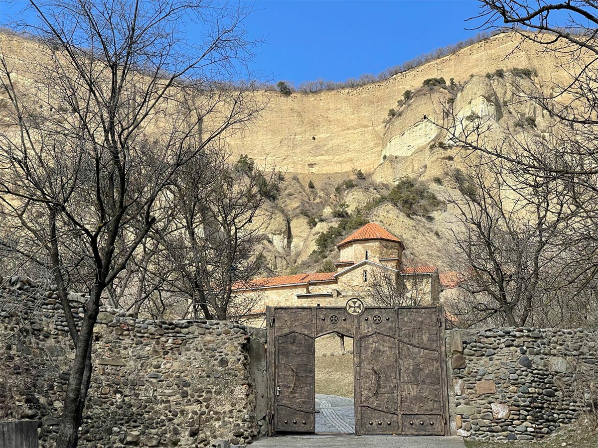 Monastery in Georgia on a mountainside, with a bright blue sky in the background