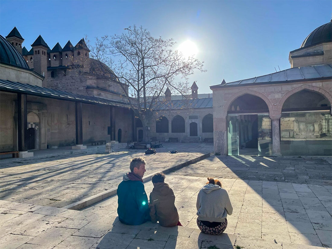 Lukas and two children sit outside the Sufi temple at sunrise—peaceful, mindful, close to nature.