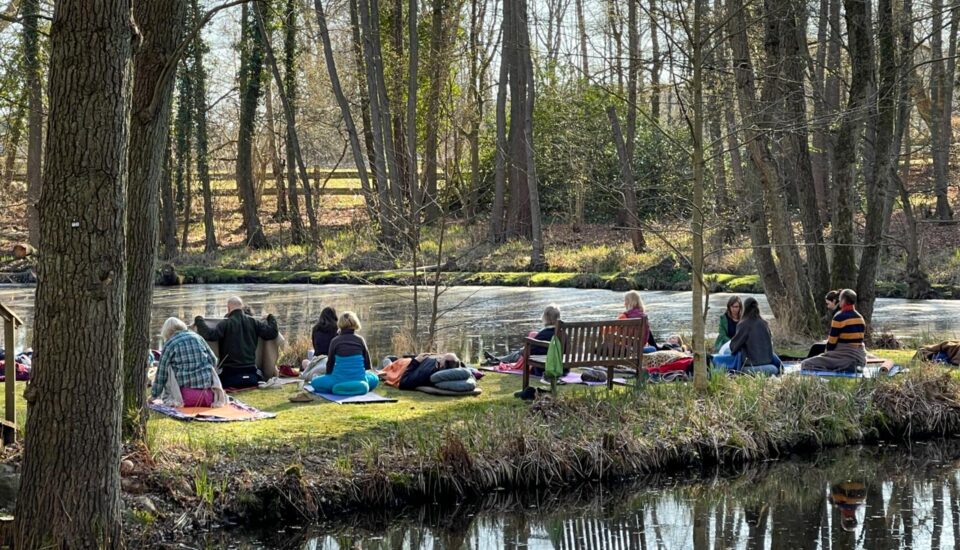Mehrere Meditierende im Haus der Stille zwischen zwei Seen, auf Halbinsel in Parklandschaft, Meditation im Sitzen und Liegen.