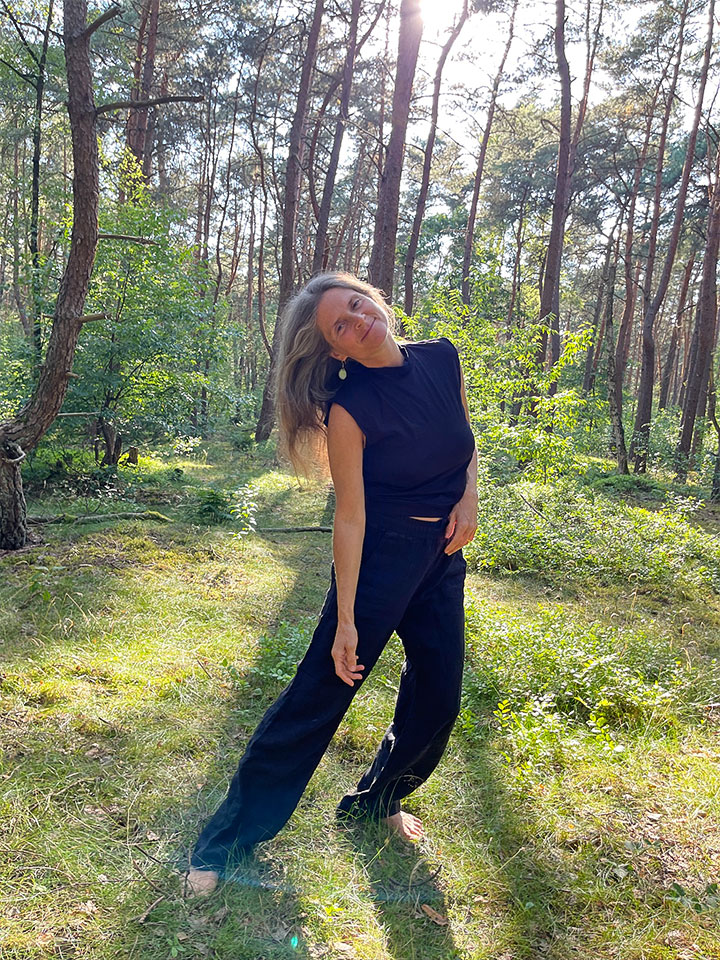 Nirmala moves playfully in the forest. She is seen from the front.