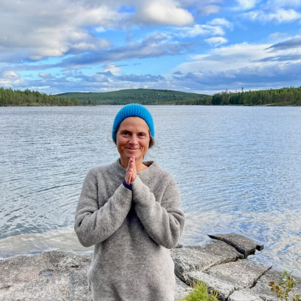 Nirmala with folded hands in front of a lake