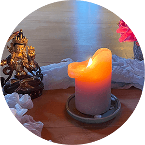 Burning candle on cloth, surrounded by golden goddess figure – symbolic, meditative, mindful.