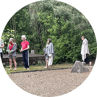 Four people practice walking meditation in the Zen garden of the ToGenJi Temple in the forest during a trauma-sensitive silent retreat.