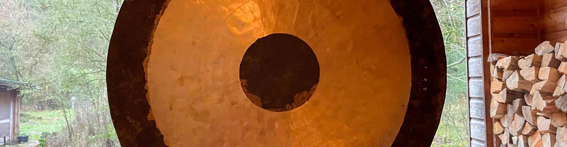 Großer gold-schwarzer Tempelgong hängt im Tempel, Symbol für Meditation und Schweigeretreats.