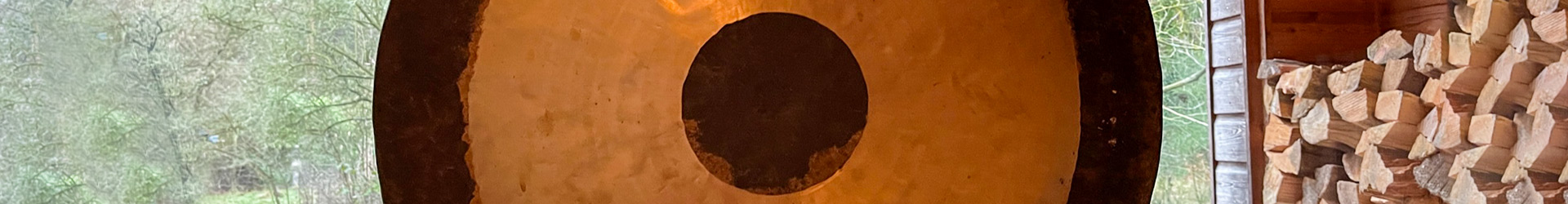 Großer gold-schwarzer Tempelgong hängt im Tempel, Symbol für Meditation und Schweigeretreats.