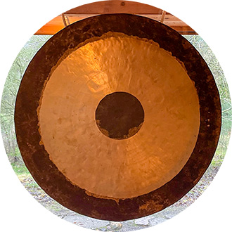 Großer gold-schwarzer Tempelgong hängt im Tempel, Symbol für Meditation und Schweigeretreats.